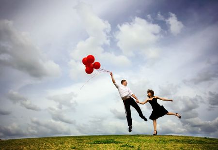 Cute Couple Flying with Red Balloons の写真素材