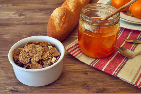 breakfast with honey, oranges, cornflakes on a rustic wooden table