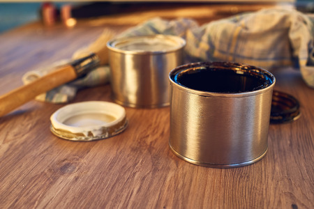 Close up on black and white paint bucket with brush and dirty rag on wooden backgroundの写真素材