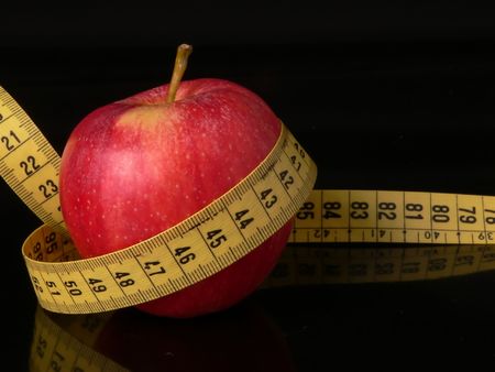 An apple with a measuring tape around as a concept of good food good healtの写真素材