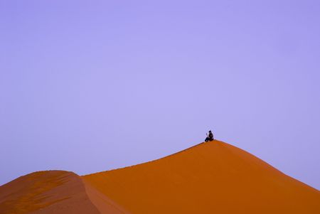 A man alone on the tip of a dune meditating, Moroccoの写真素材
