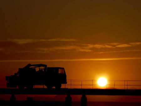 red sunset with truck silhouette on a pier in progressの写真素材