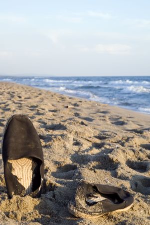 Stylish beach shoes photographed on the sand at sunset. Composition leaves a lot of space for typingの写真素材