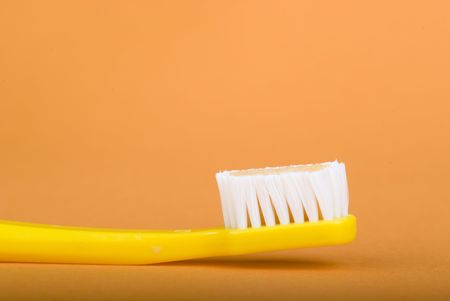 yellow toothbrush on an orange background.の写真素材