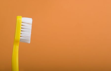 yellow toothbrush on an orange background.の写真素材