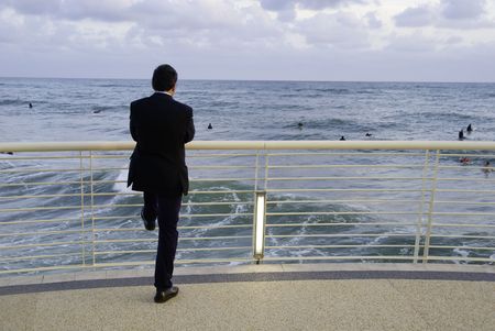 Businessman admiring young surfer at the seaside. Good concept for working stress, holiday concep.の写真素材