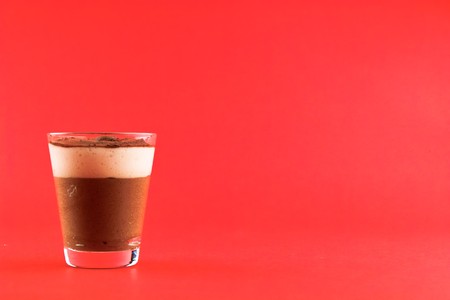 Glass of mousse a chocolat on a red background. Space left for text.の写真素材