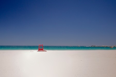 Red safeguard cabin isolated in the beautiful beach of camps bay with a marvelous emerald sea in the background in cape townの写真素材