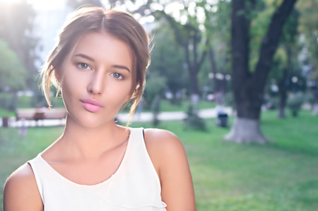 Bautiful girl wearing a white shirt poses in a city parkの写真素材