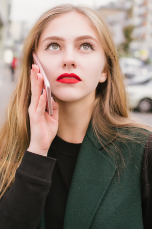 Young girl talking to mobil phone illuminated by a red street neon only. Flare improves the mood of the compositionの写真素材