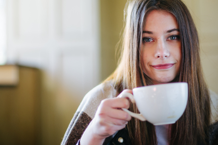 Beautiful brunette drink tea and warm herselfの写真素材