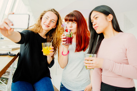 Three young girlfriends taking selfieの写真素材