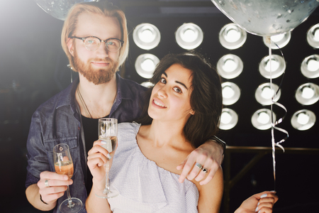 Young couple celebrates their love toasting with champagne glass with a hollywood style backlight, flare  used to increase the mood and tones of compositionの写真素材
