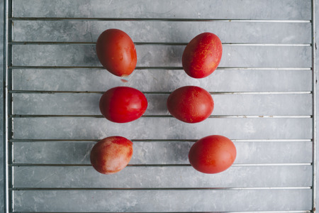 Red colored eggs with red tint are displayed on a metallic grate  top view over a gray concrete backgroundの写真素材