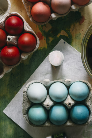 Dyeing eggs for Easter holidays, colored eggs with blue tint and different tonality ainside a package over a gray concrete backgroundの写真素材