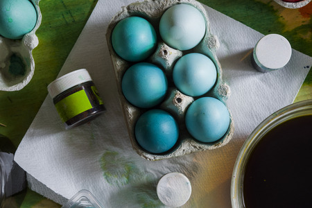 Dyeing eggs for Easter holidays, colored eggs with blue tint and different tonality ainside a package over a gray concrete backgroundの写真素材