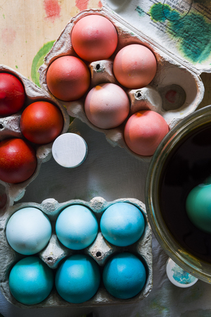 Dyeing eggs for Easter holidays, colored eggs with blue tint and different tonality ainside a package over a gray concrete backgroundの写真素材