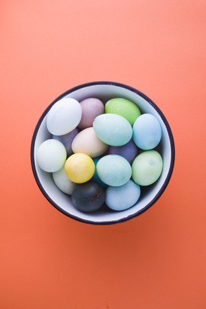 Colored eggs with pastelle tones inside a metallic bowl over a pink background, back lighted,  easter concept,holiday.の写真素材