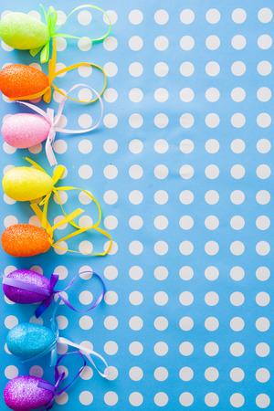 Colored decoration eggs for Easter holidays over a blue and pois white backgroundの写真素材