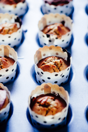 Close up of some Freshly baked pumpkin's muffin lined on an aluminium baking tray for halloween displayed on a blu rustic board, flat lay top view,natural backlight.の写真素材