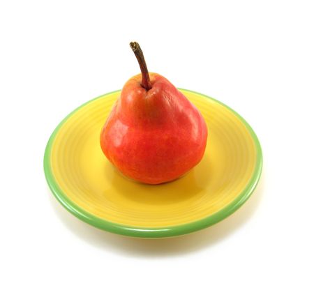 image of a red pear on a yellow plateの写真素材