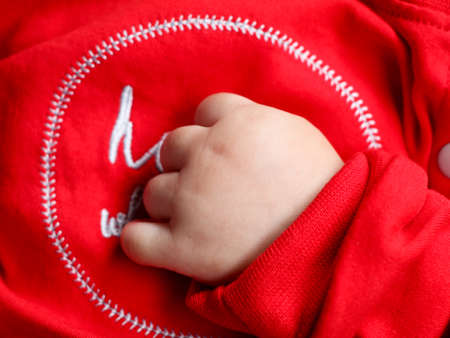 Close up shot of the cute hands of a baby in red dress  while sleepingの写真素材