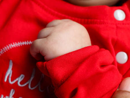 Close up shot of the cute hands of a baby in red dress  while sleepingの写真素材