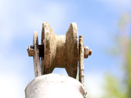 Low angle shot of an old well pulley against sky fixed on an iron post, vintage
