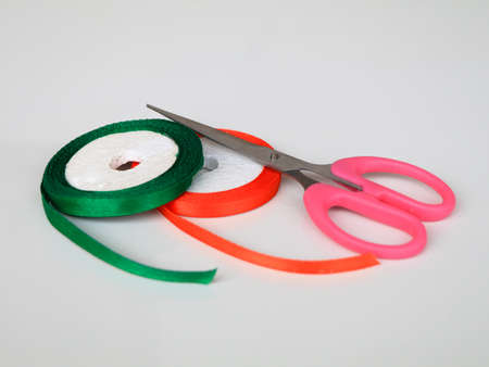 Satin ribbon rolls with scissors  against white background, isolatedの写真素材