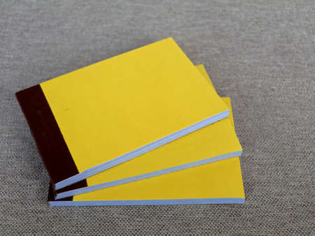 Yellow color bill books or receipt books on a cream color furnishing cloth, close up shot