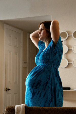 A pregnant woman at the start of her labor stretches for a moment between contractions.  She looks a...