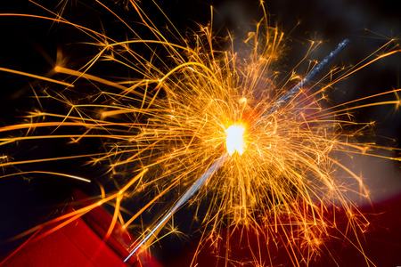 Close up image of a sparkler burned halfway down with sparks flying all around.の写真素材