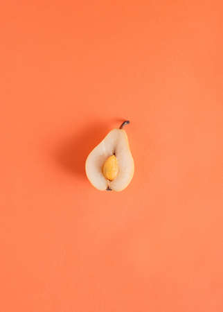 Flat lay made of halved pear and peeled kumquat on pastel orange background. Minimal natural fruit food concept.の写真素材