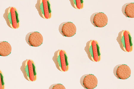 Hot dog and hamburger fast food pattern on pastel beige background. Minimal junk food flat lay...