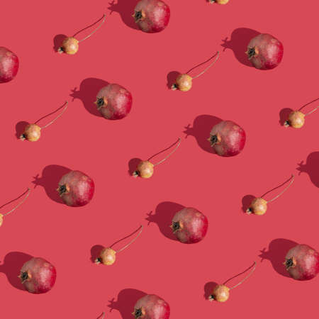 Natural creative pattern made of healthy, sunlit wild and cultivated pomegranates on a bold red background. Minimal flat lay concept.の写真素材