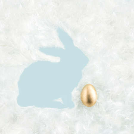 2021 creative layout made of pastel white fluffy seed hairs and gold Easter egg. Minimal flat lay...