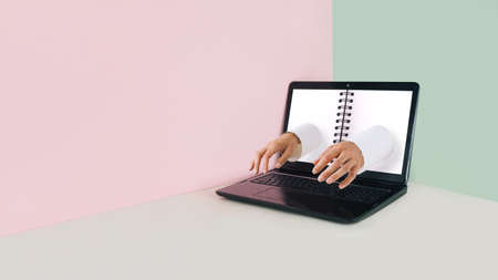 Minimal workspace made of laptop with notepad and male hands typing on keyboard.の写真素材