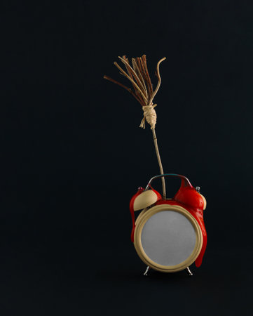 2021. Minimal abstract Halloween scene made of bloody alarm clock and witchâs broom isolated on the black background. Halloween party invitation card concept with copy space.の写真素材
