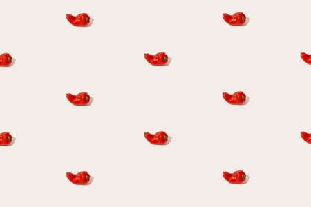 Aesthetic vegetable food pattern made of red sweet peppers isolated on the pastel beige background. Sun and shadows. Source of vitamin C and vegan kitchen ingredient idea. Minimalist texture concept.の写真素材