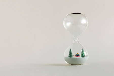 2022. Fir christmas trees and Santaâ€™s sleigh with presents, standing in the hourglass...