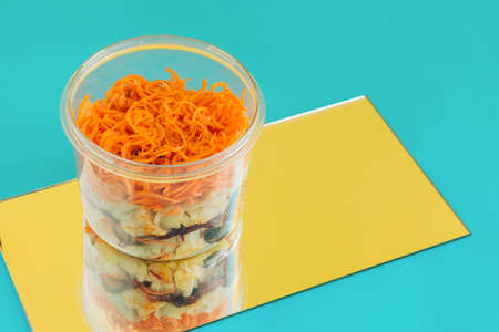 Chopped cabbage, carrot and beet in transparent dish reflected in the mirror on yellow-blue background. Colorful mixed fermented vegetable salad. Natural probiotics source idea. Healthy food concept.の写真素材