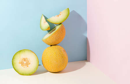 Minimal abstract creative summer fruit scene. Slices of juicy fresh melon on isolated pastel beige, pink and blue background with copy space. Aesthetic concept of raw healthy food.の写真素材