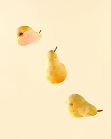 Minimal raw vegetarian food scene with pears floating on isolated pastel yellow background. Concept of minimal summer or autumn fruit. The idea of organic agricultural products.の写真素材