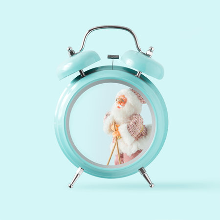 2023. Santa Claus on skis in alarm clock with isolated pastel blue background. Minimal New Year...