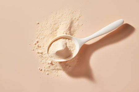 Spoon with BCAA, beta-glucan, anabolic whey protein powder or nutrition yeast. Isolated beige color background. Top view. Minimal flat lay. Concept of food or dietary supplements.の素材