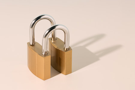 Brass padlocks with shiny metallic shackle, isolated on beige background with shadow, symbolizing...