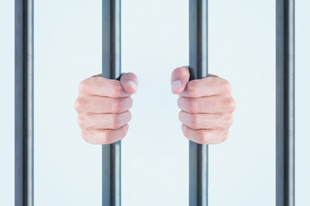 Human hands gripping metal bars, symbolizing prison, restriction, captivity, front view, white background. Minimal concept of isolation, criminal, conviction, repression or dungeonの写真素材