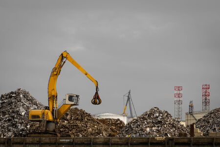How all metal things will end. Scrapyard with big yellow machine to move metal parts around.