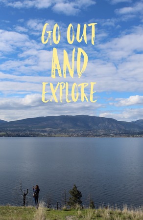 Inspirational text on scenic lake and mountains landscape view with woman standing on hillside. Yellow text. Go out and Explore.の写真素材