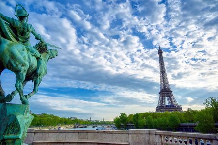 The Eiffel Tower across the Seine River in Paris, France on a sunny day with beautiful clouds.